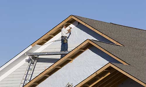 Workers on a platform installing new siding on a two-story home