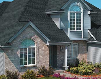 Front view of a typical mid-class home with charcoal black GAF shingles on its roof
