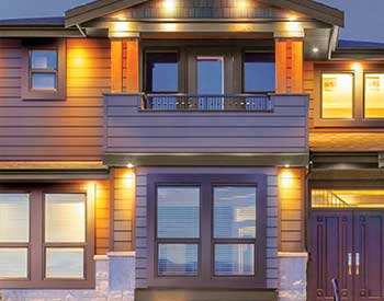 Front view of a home in the evening with its front lights on and purple-ish Royal siding